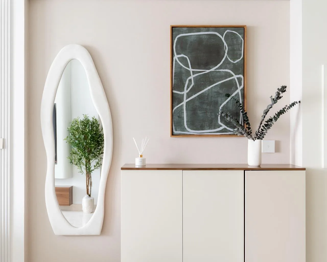 Entrance vignette in Palace Emaar Beachfront with sculptural plaster mirror, abstract art and walnut-top console